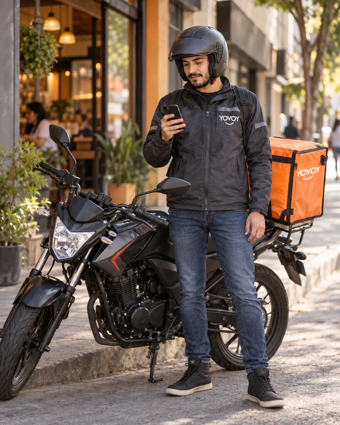 Repartidor YOVOY consulta su celular junto a una motocicleta